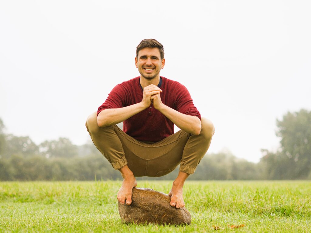 Jonte Witte in der Hocke auf Stein auf einer Wiese